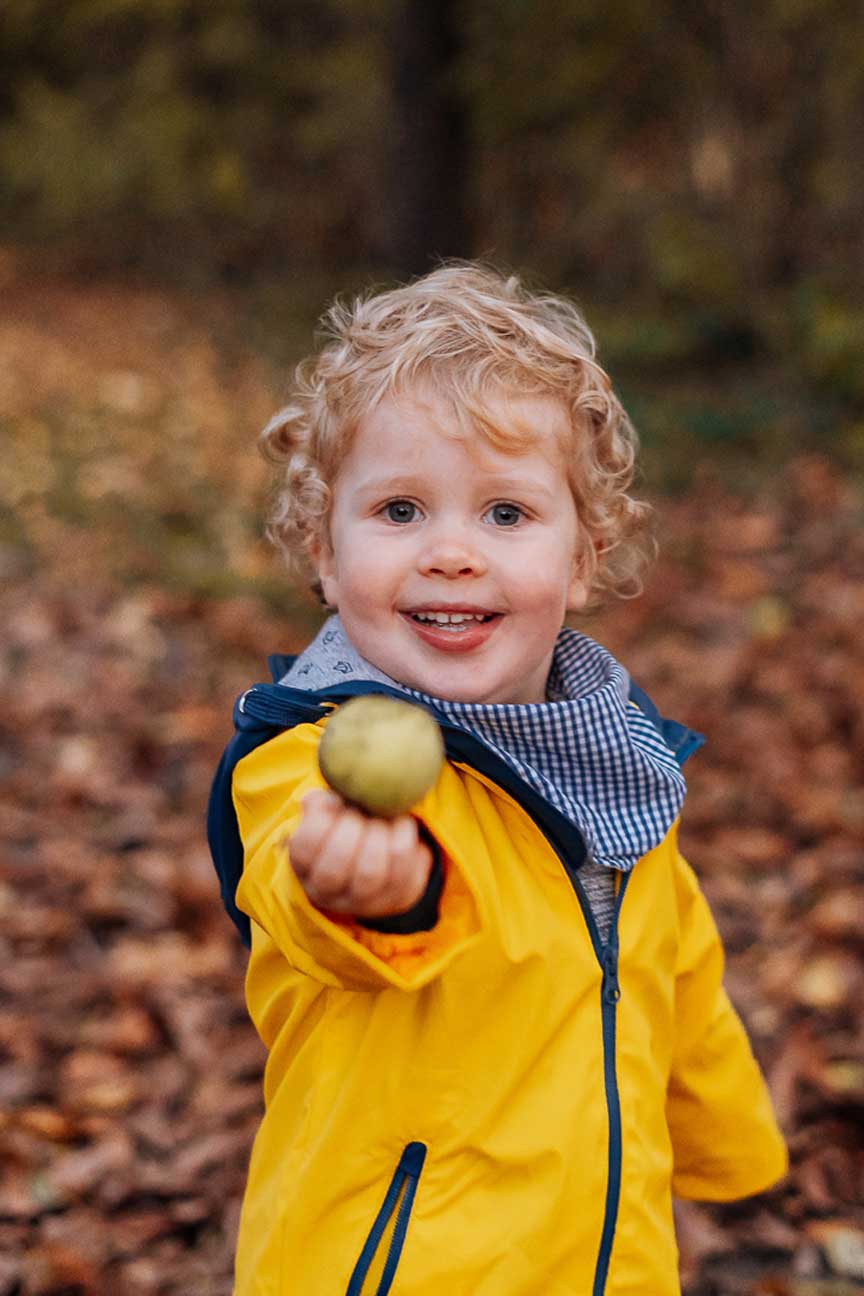 Kind mit Apfel im Herbstlaub
